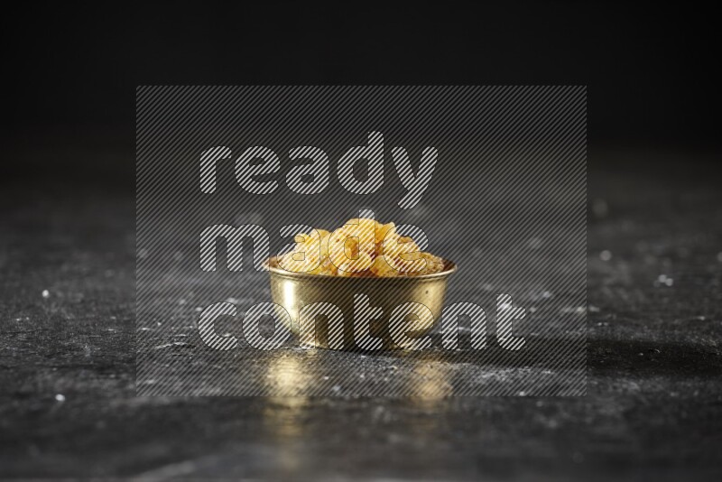 Dried fruits in a metal bowl in a dark setup