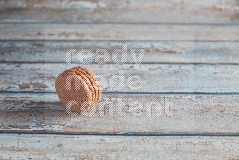 45º Shot of Brown Hazelnuts macaron on light blue wooden background