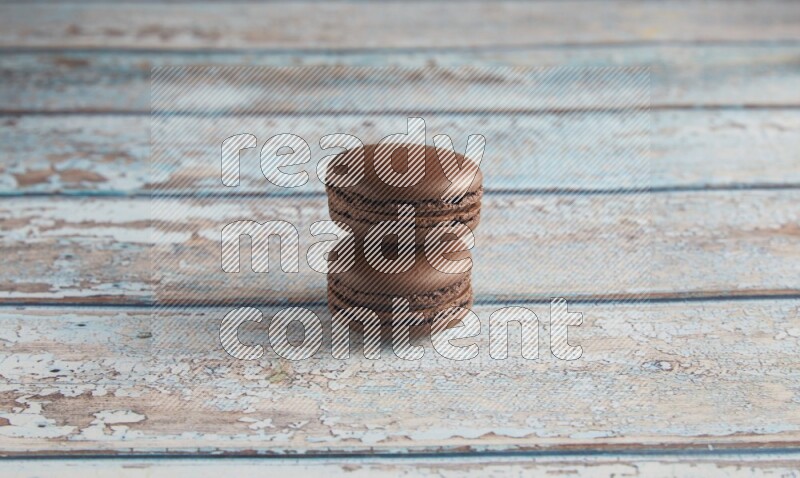 45º Shot of two Brown Dark Chocolate macarons on light blue wooden background