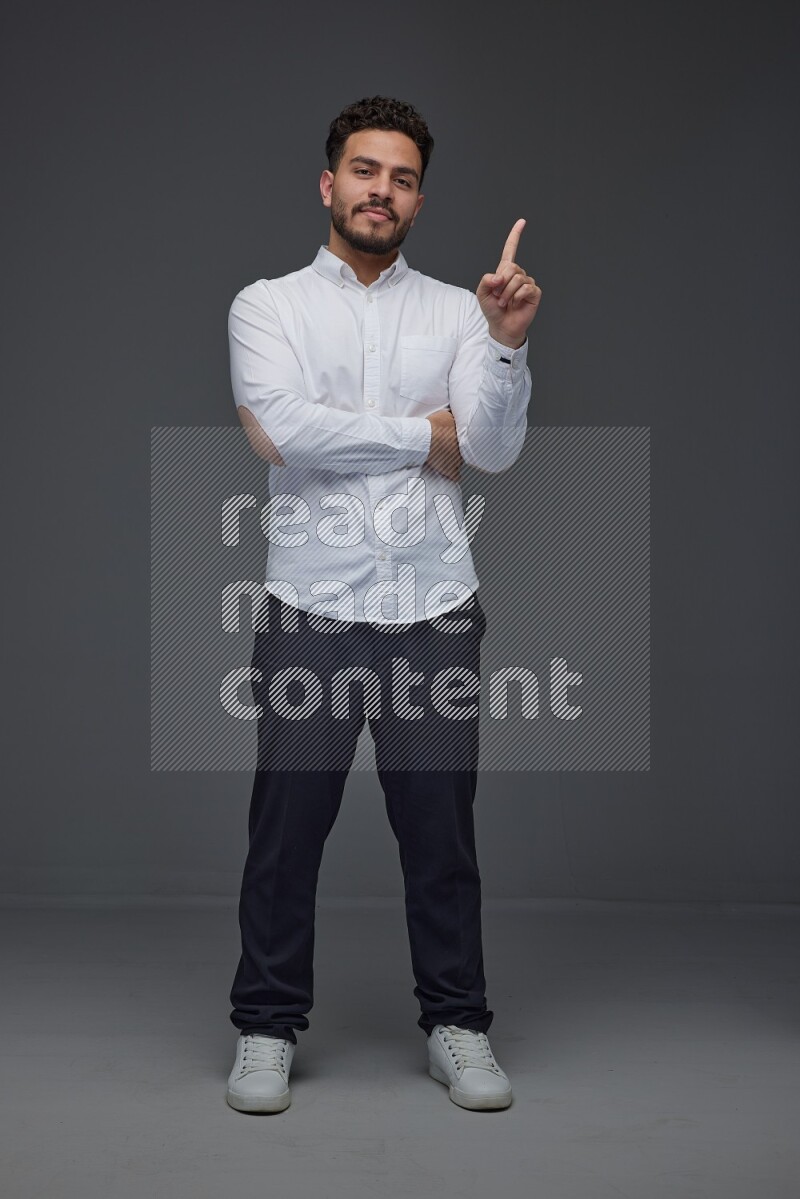A man wearing smart casual standing and making multi hand gestures eye level on a gray background