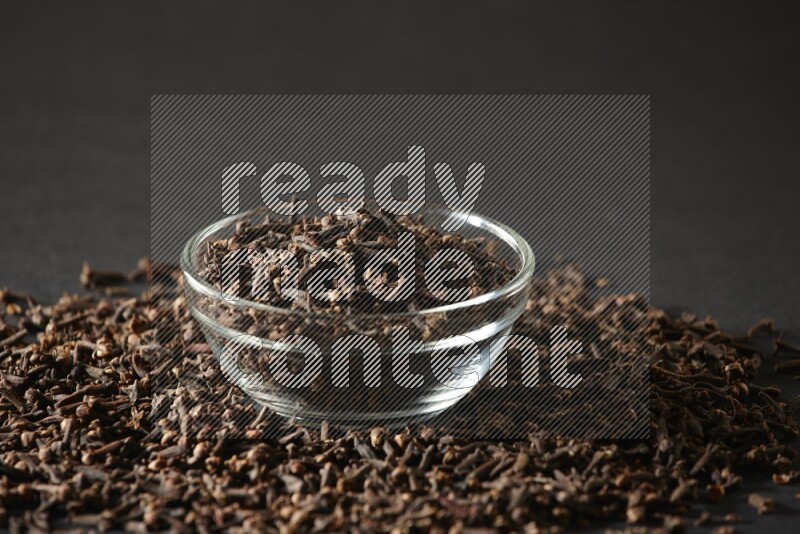 A glass bowl full of cloves on a black flooring