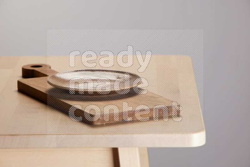 multi-colored pottery Plate placed on a  wooden rectangular cutting board on the edge of wooden table