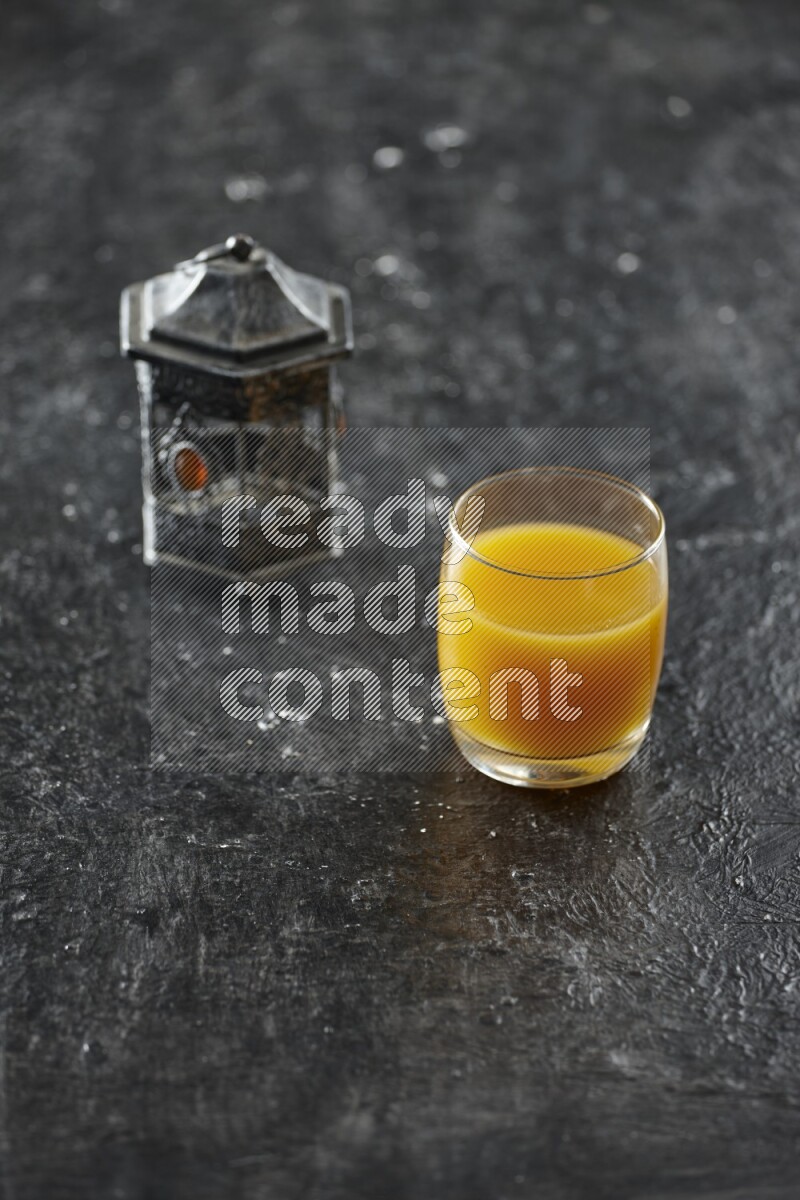 A silver lantern with different drinks, dates, nuts, prayer beads and quran on textured black background