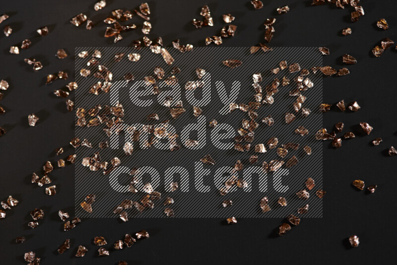 Bronze shimmering fragments of glass scattered on a black background