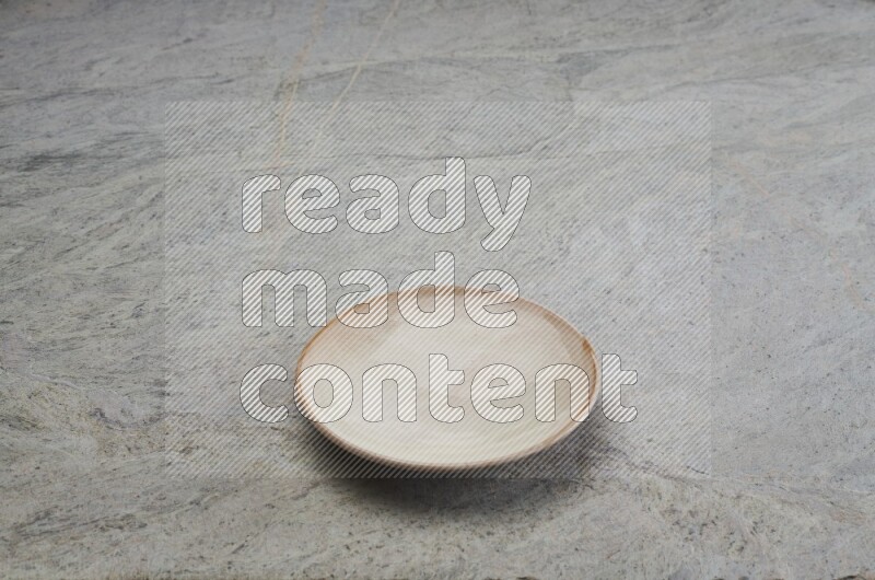 A beige pottery plate on grey marble background