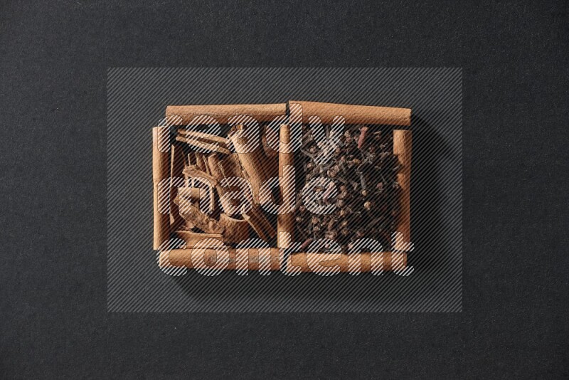 2 squares of cinnamon sticks full of cloves and cinnamon on black flooring