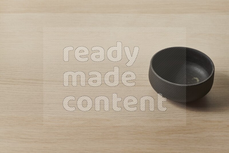 A black pottery bowl on light wooden background