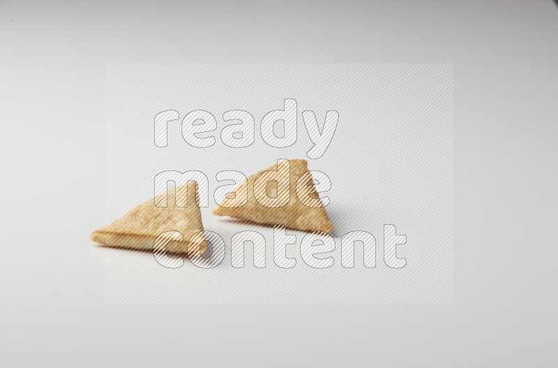 Two fried sambosas on a white background