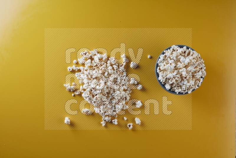 A blue pottery bowl full of popcorn with popcorn beside it on a yellow background in different angles