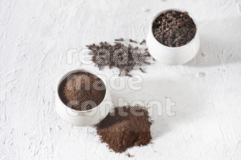 وعاءين من السيراميك بيج اللون، أحدهما مملوء بالقرنفل والآخر مملوء بالبودرة على أرضية بيضاء