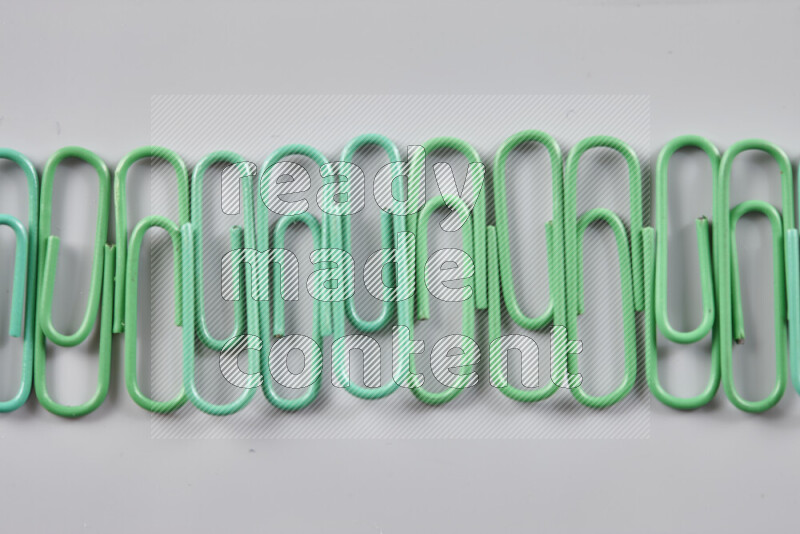 Green paper clips isolated on a grey background