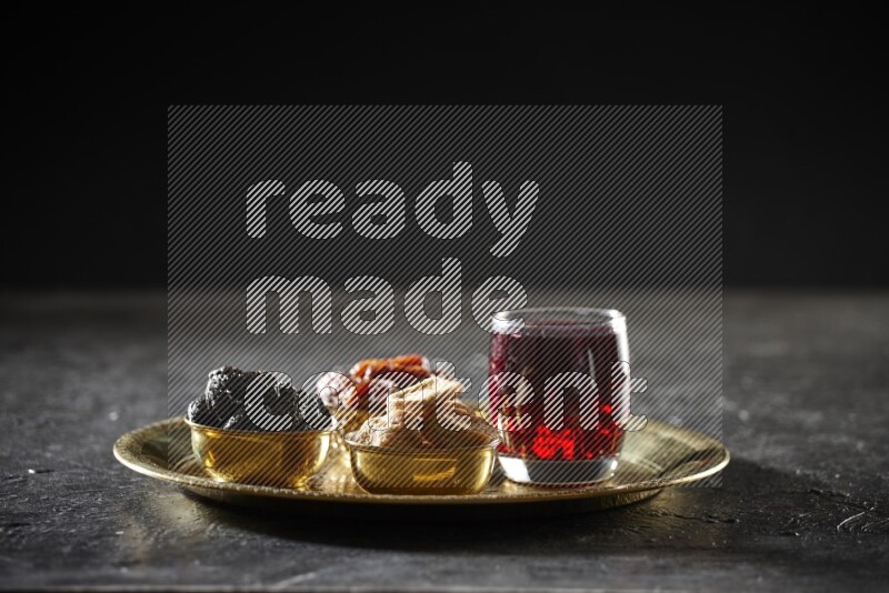 Dried fruits in metal bowls with Hibiscus on a tray in dark setup