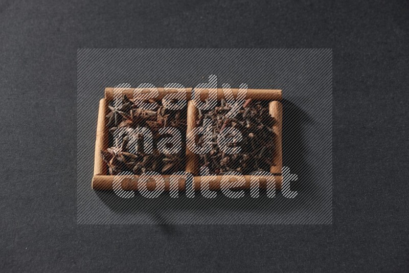 2 squares of cinnamon sticks full of star anise and cloves on black flooring