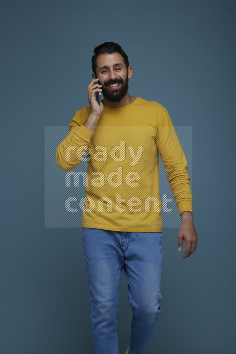 A man having a calling in a blue background wearing a yellow shirt