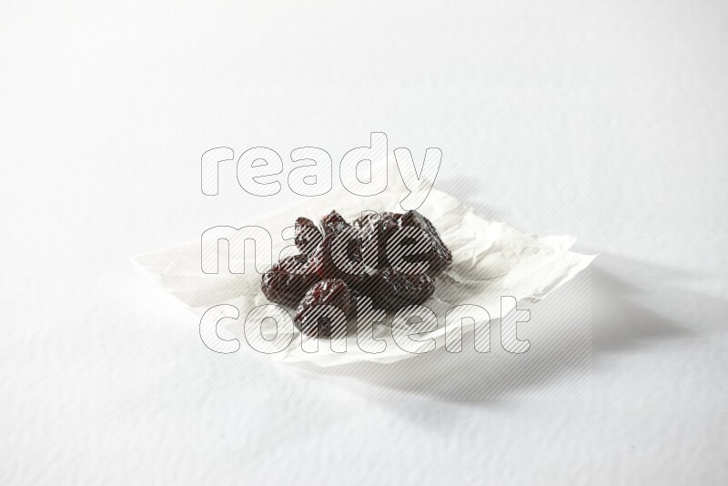 Dried plums on a crumpled piece of paper on a white background in different angles