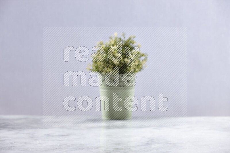 Artificial plant in green decorative pot on grey marble background