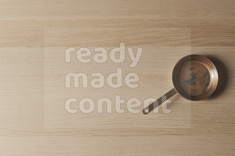 A small copper pan on light wooden background