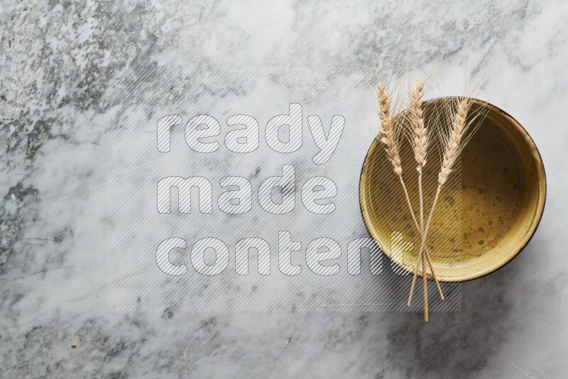 Wheat stalks on multicolored pottery oven plate on grey marble background