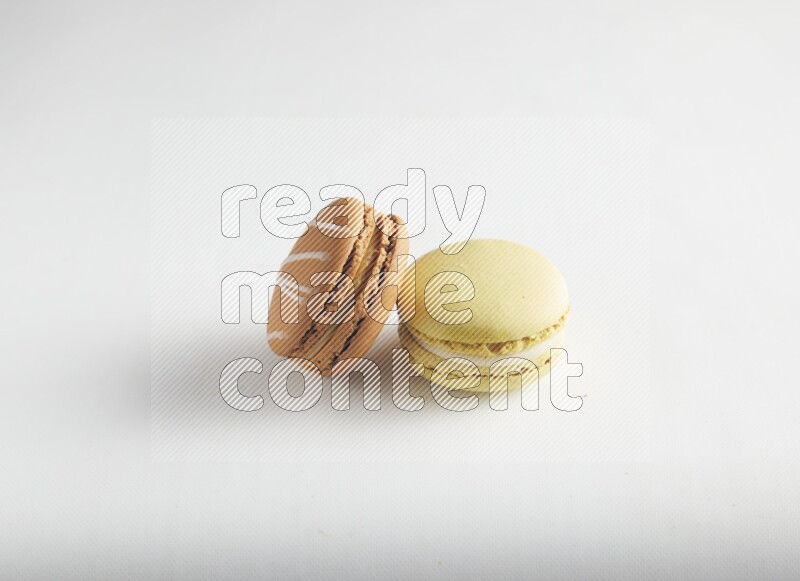 45º Shot of of two assorted Brown Irish Cream, and Yellow Lime macarons on white background