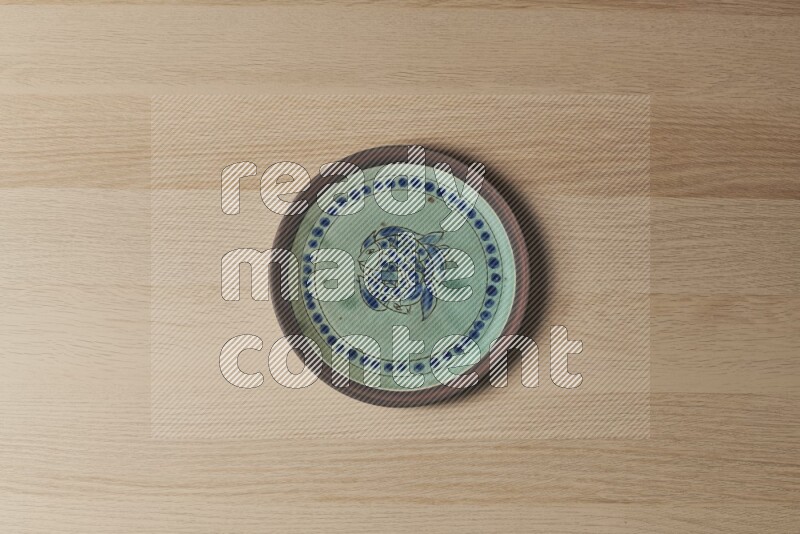 A decorative pottery plate on light wooden background