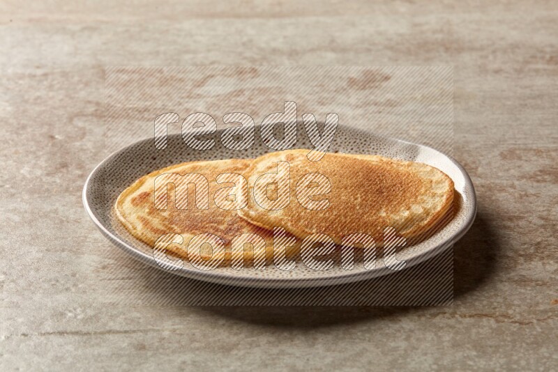 Two stacked plain pancakes in an irregular plate on beige background