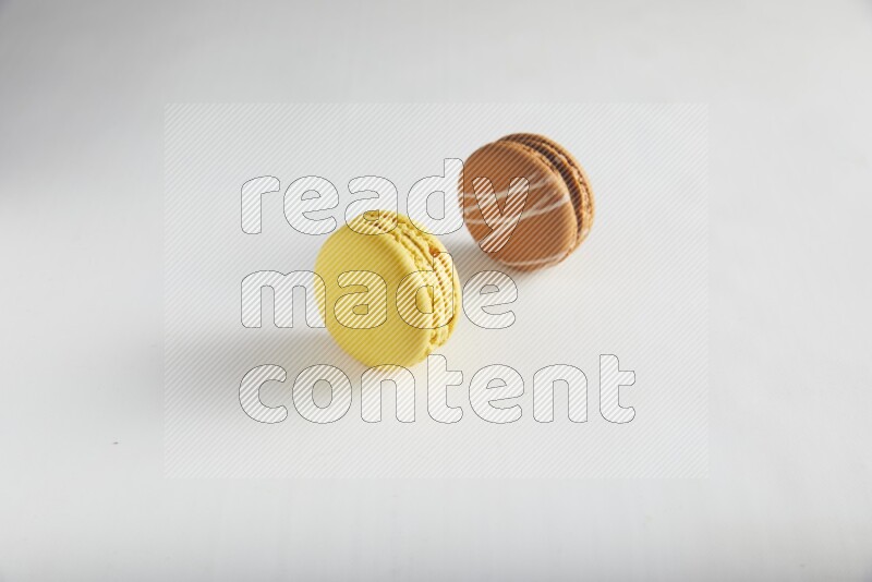 45º Shot of of two assorted Brown Irish Cream, and Yellow Lemon macarons on white background