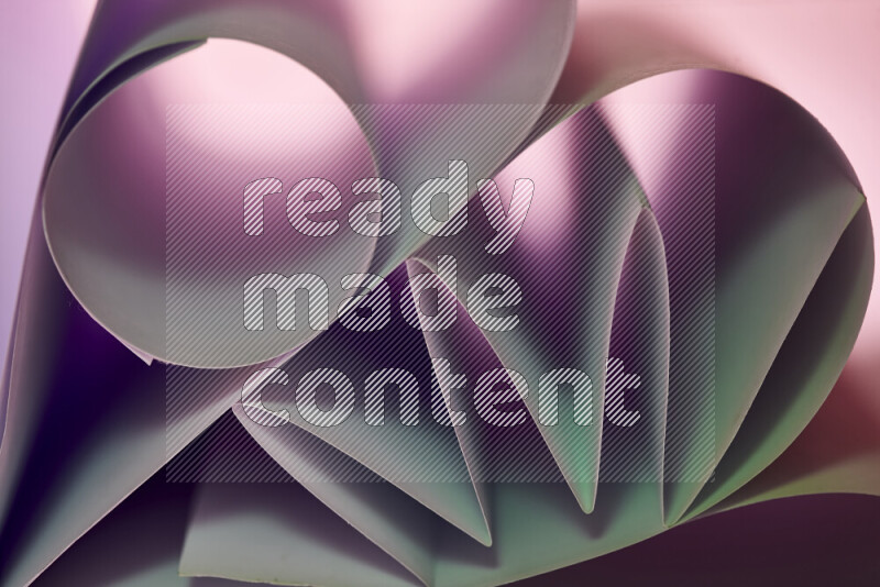 An artistic display of paper folds creating a harmonious blend of geometric shapes, highlighted by soft lighting in green and purple tones