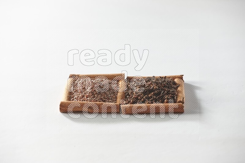 2 squares of cinnamon sticks full of cloves and flaxseeds on white flooring