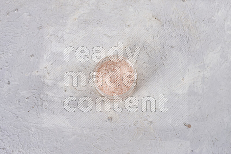 A glass jar full of fine himalayan salt on white background