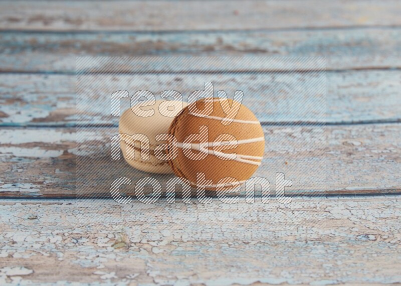 45º Shot of of two assorted Brown Irish Cream, and White Caramel fleur de sel macarons on light blue background
