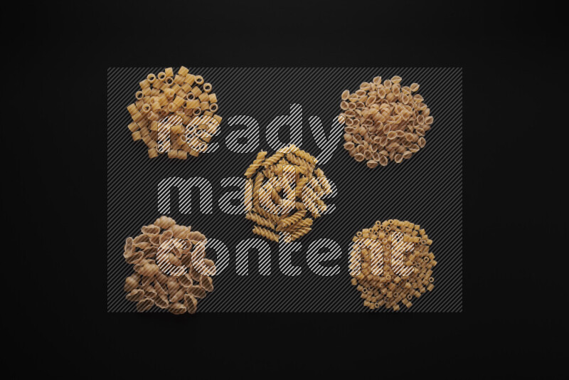 Different pasta types in bunches on black background