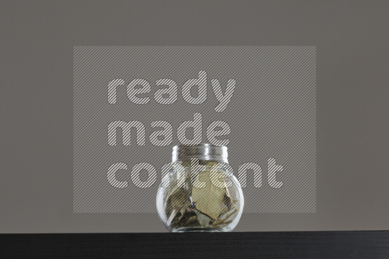 Bay laurel leaves in a glass jar on black background