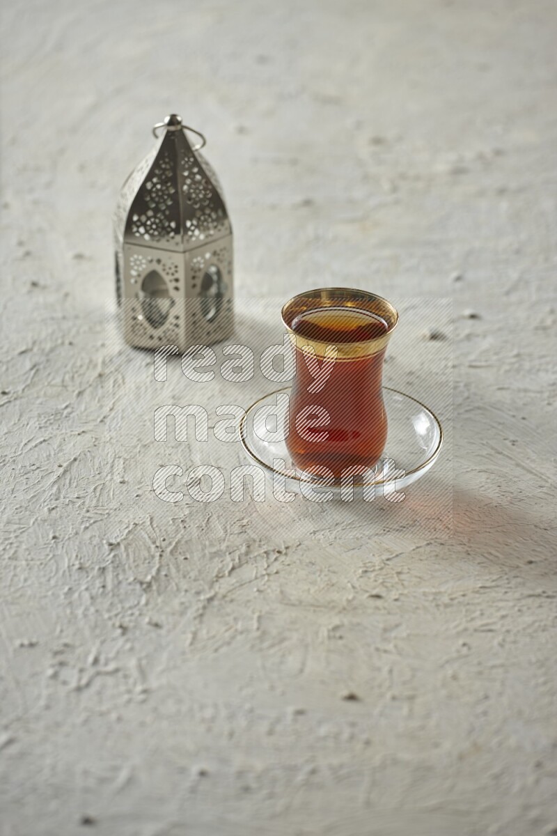 A silver lantern with different drinks, dates, nuts, prayer beads and quran on textured white background