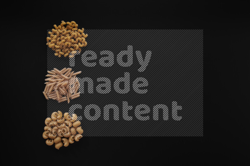 Different pasta types in 3 bunches on black background