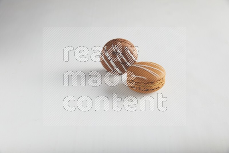 45º Shot of of two assorted Brown Irish Cream, and Brown white Chocolate Caramel macarons on white background