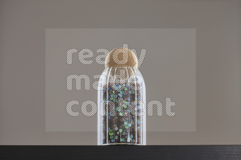Sequins in a glass jar on black background