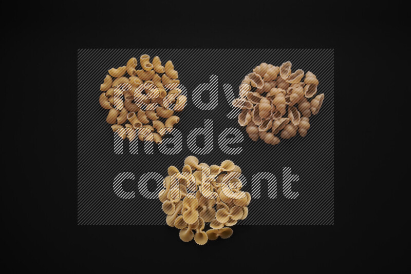 Different pasta types in bunches on black background