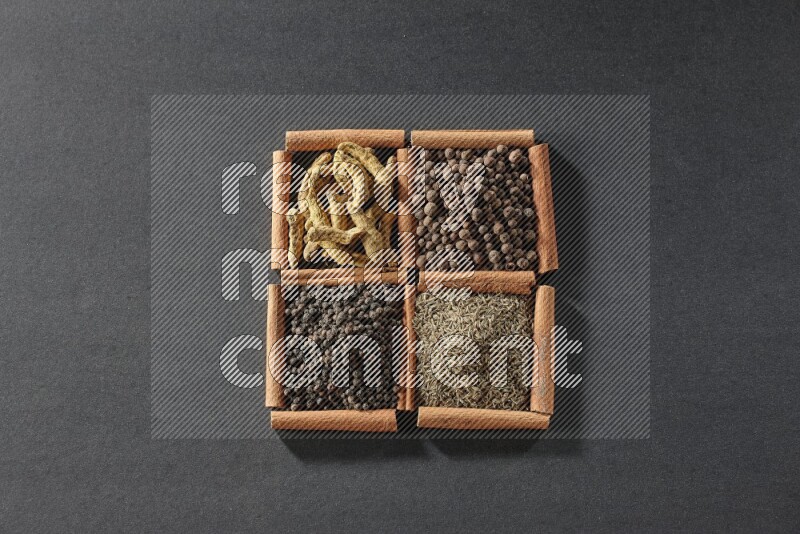 4 squares of cinnamon sticks full of black pepper, cumin, allspice and turmeric fingers on black flooring