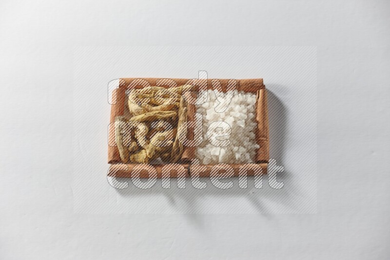 2 squares of cinnamon sticks full of turmeric fingers and white salt on white flooring