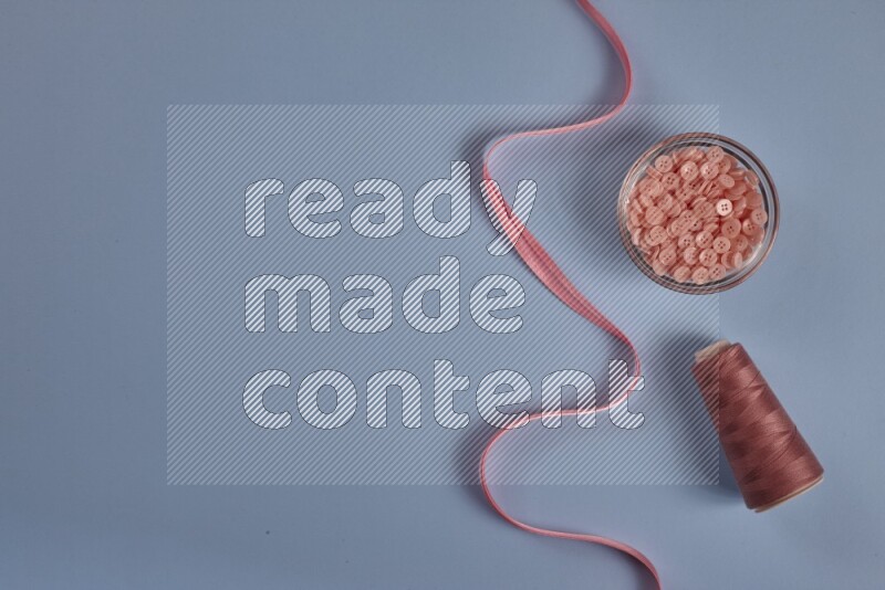 مجموعة من أدوات الخياطة والتفصيل زهرية اللون على خلفية زرقاء