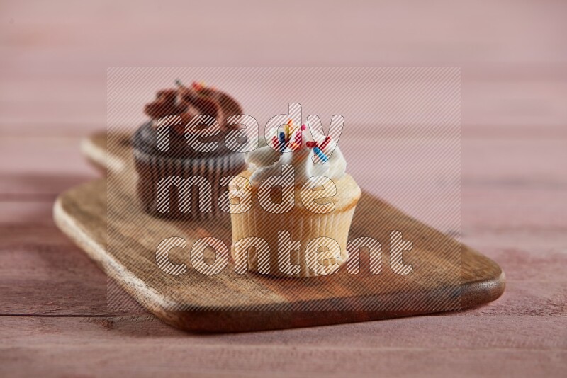 Vanilla mini cupcake topped with cream on a wooden board