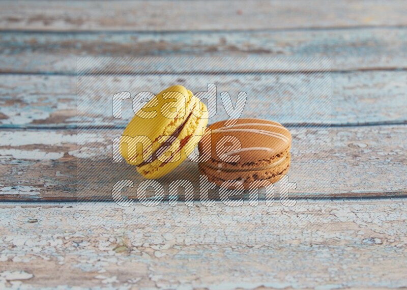 45º Shot of of two assorted Brown Irish Cream, and Yellow Lemon macarons on light blue background