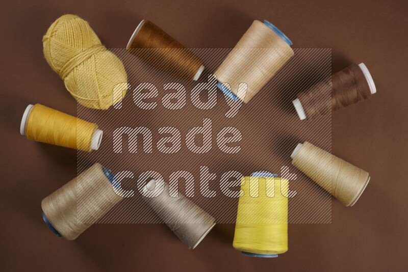 A yellow collection of sewing and tailoring tools arranged on a brown background