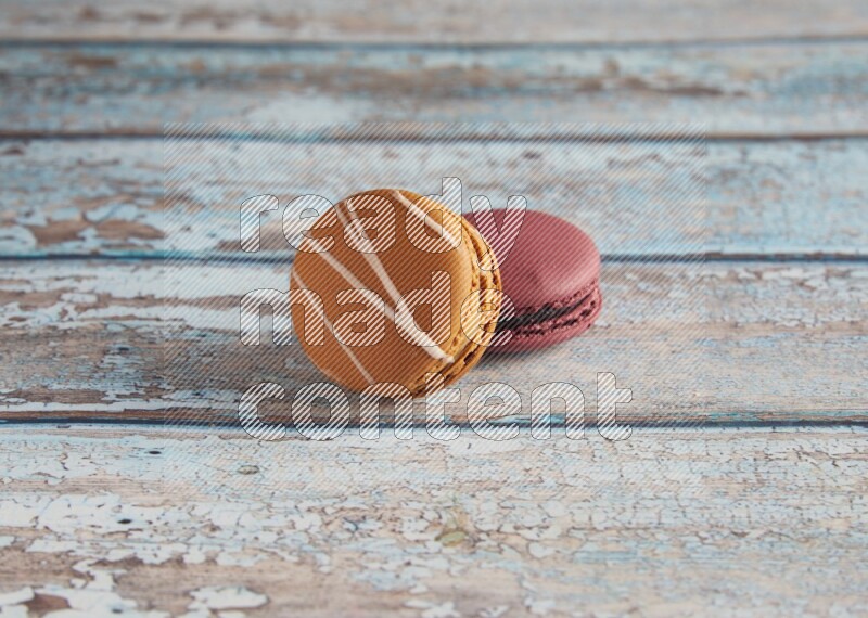 45º Shot of of two assorted Brown Irish Cream, and Red Cherry macarons  on light blue background