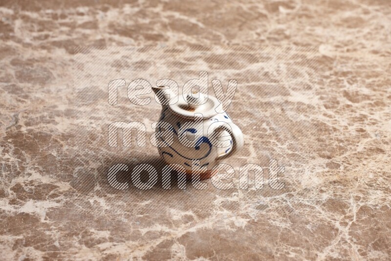 A pottery teapot on beige marble background