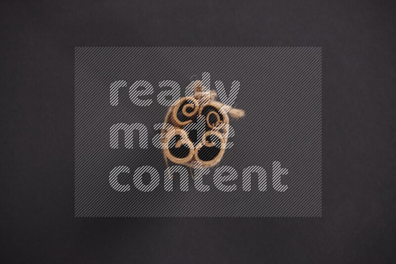 4 أعواد من القرفة مربوطة علي خلفية سوداء