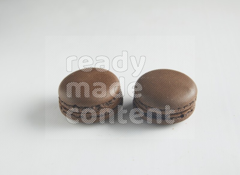 45º Shot of two Brown Dark Chocolate macarons on white background