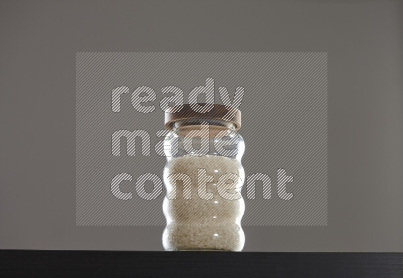 White rice in a glass jar on black background