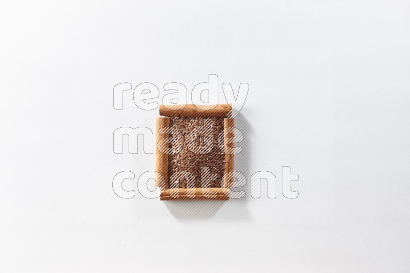 A single square of cinnamon sticks full of flaxseeds on white flooring