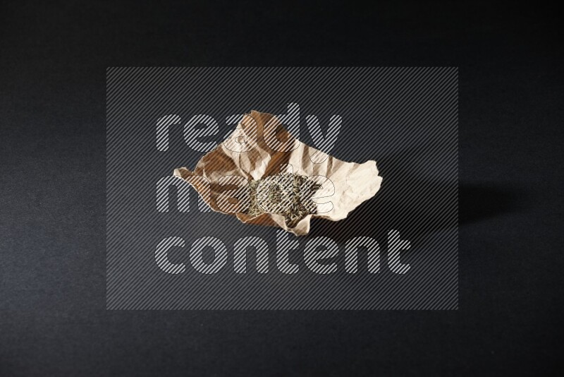 Cumin seeds in a crumpled piece of paper on black flooring